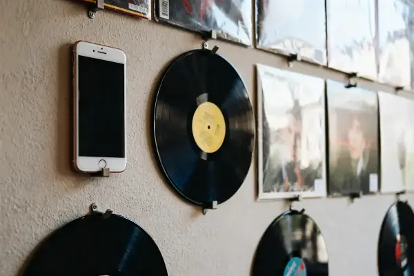 Un mur de vinyles avec un téléphone fixé, décor rétro et moderne.