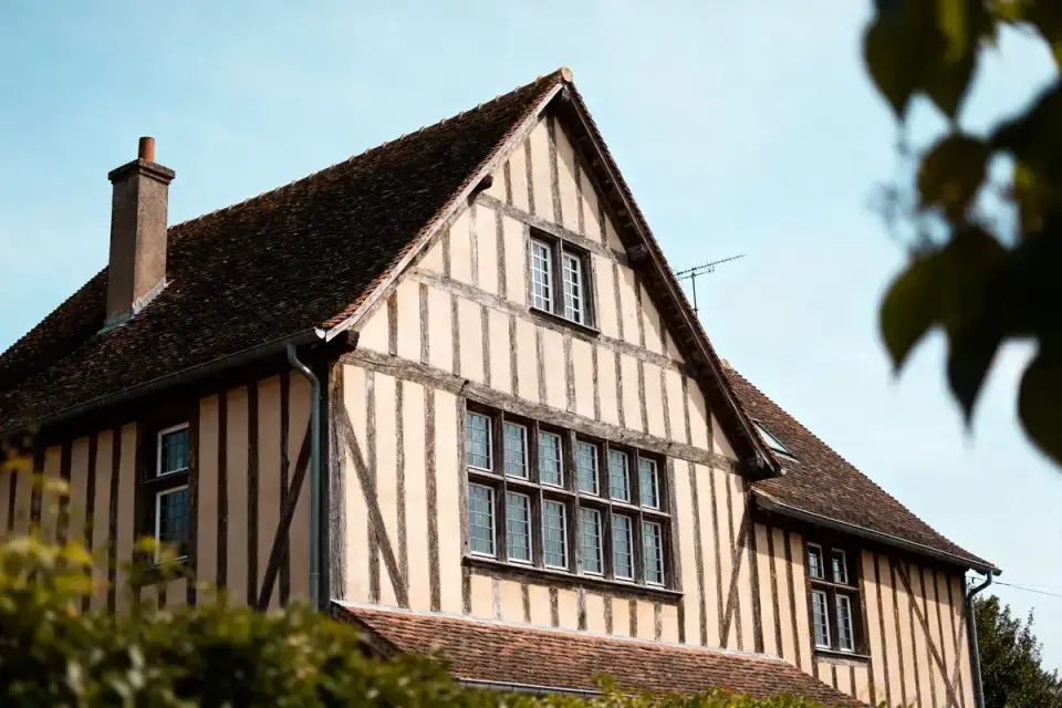 Maison en bois à colombages illustrant l'architectural style Tudor avec fenêtres à meneaux.