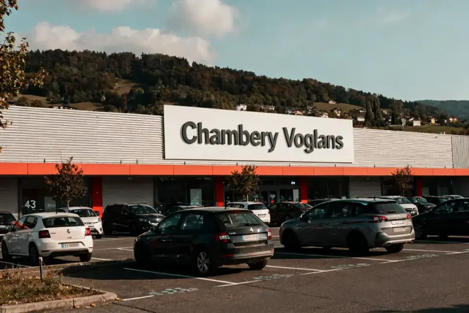 Façade du magasin But Chambéry Voglans avec voitures garées devant et colline en arrière-plan