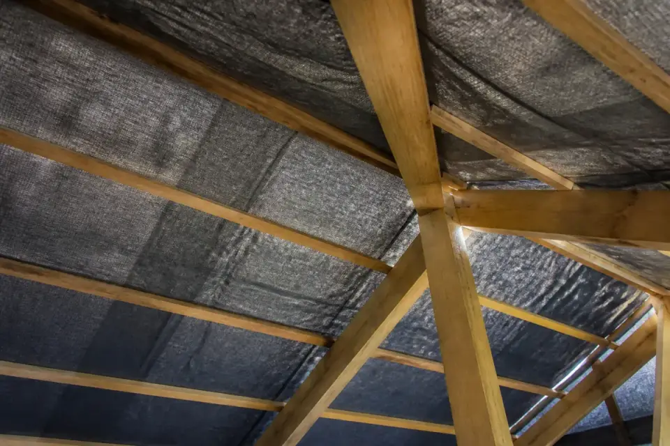 Structure de toiture avec poutres en bois et bâche noire tendue pour une isolation optimale.
