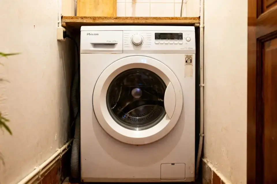 Lave-linge encastré avec tuyau indiquant la hauteur evacuation lave linge dans un espace réduit